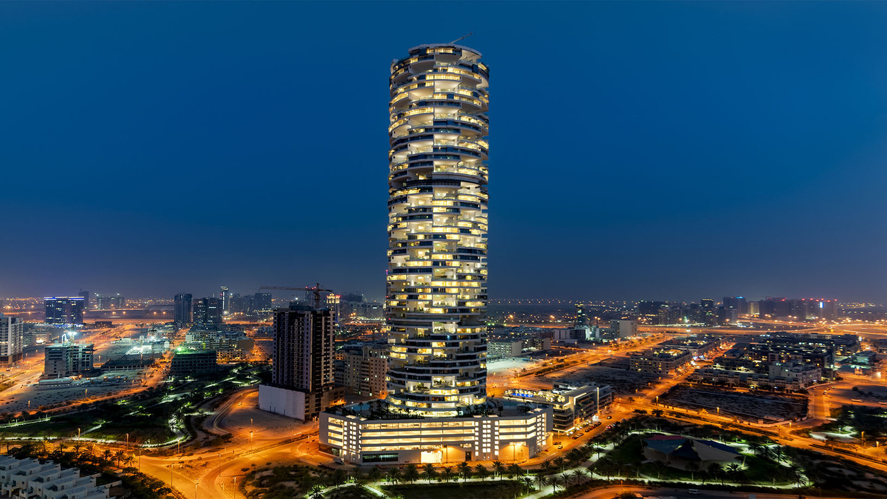 An image of the Five Hotel in JVC at night with the building lit up
